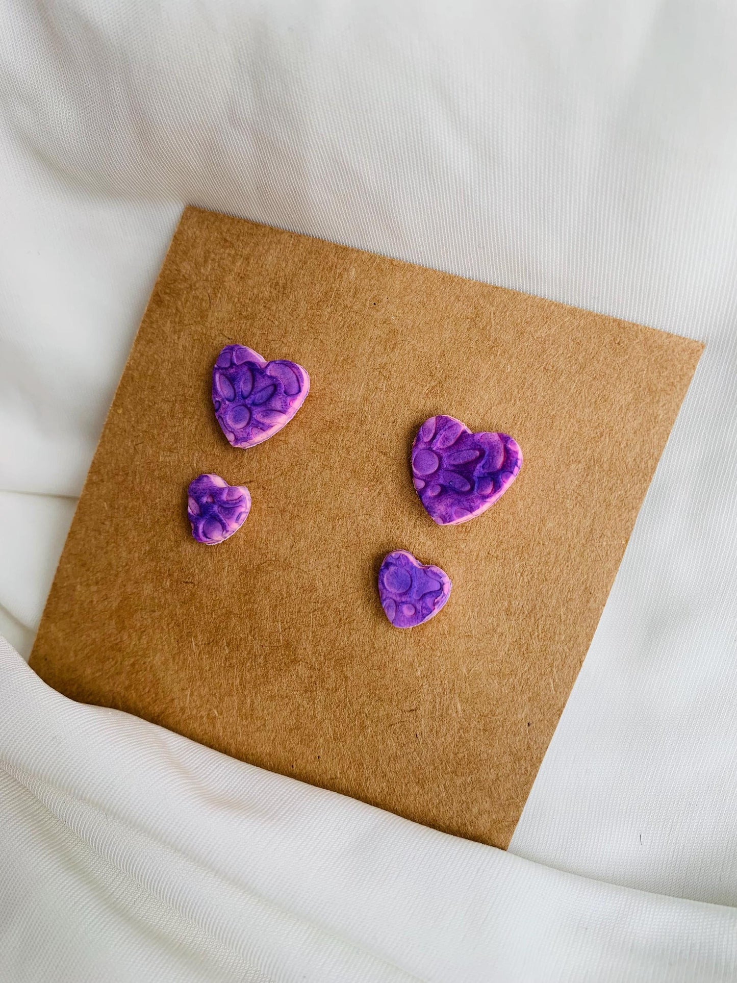 Floral pattern embossed in two sizes of stud earrings in purple colour