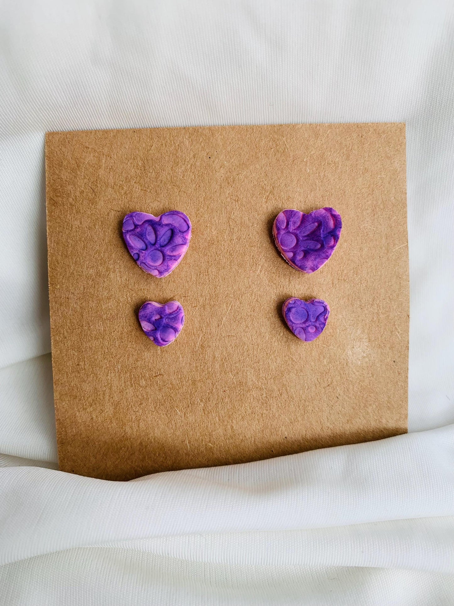 Floral pattern embossed in two sizes of stud earrings in purple colour